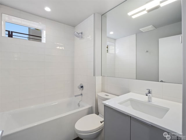 full bathroom featuring vanity, tiled shower / bath combo, tasteful backsplash, tile walls, and toilet