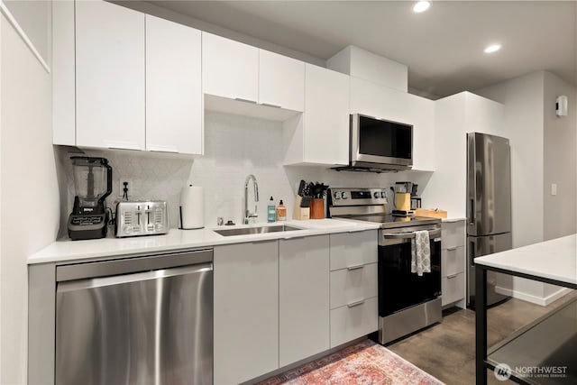 kitchen featuring a sink, white cabinets, light countertops, appliances with stainless steel finishes, and tasteful backsplash