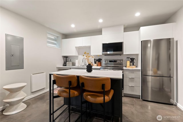 kitchen with a center island, stainless steel appliances, light countertops, white cabinets, and electric panel