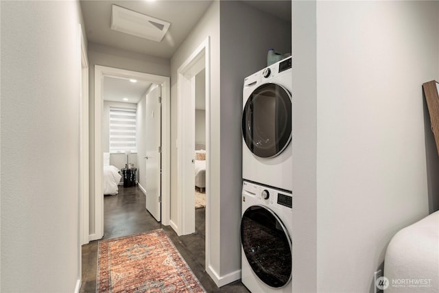 laundry room with baseboards, laundry area, and stacked washer / drying machine