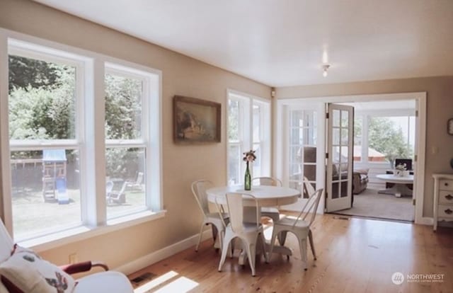 dining space with hardwood / wood-style flooring, plenty of natural light, and french doors