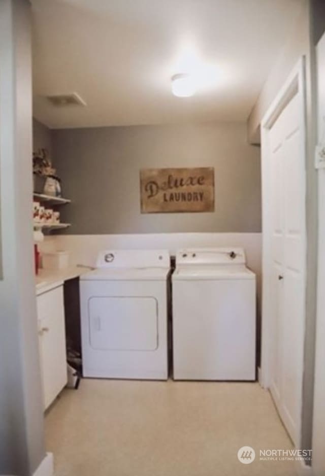 washroom featuring washer and dryer, cabinets, and light colored carpet