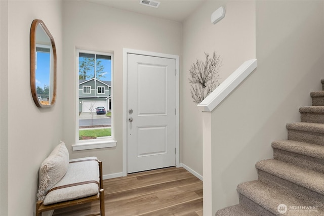 entryway with plenty of natural light, stairs, visible vents, and wood finished floors