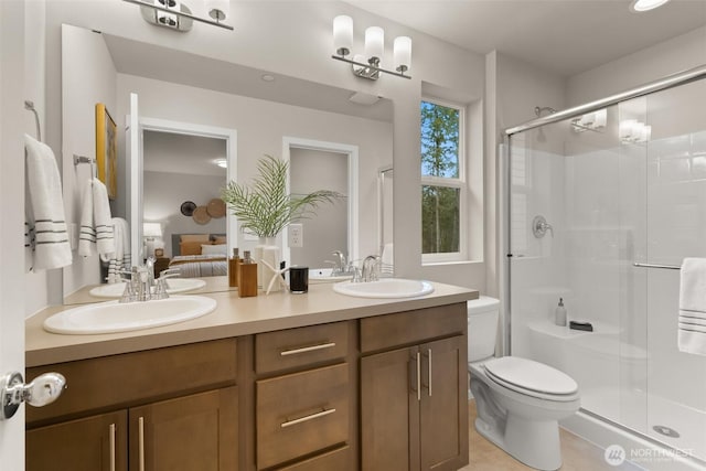 ensuite bathroom with a sink, a shower stall, toilet, and double vanity