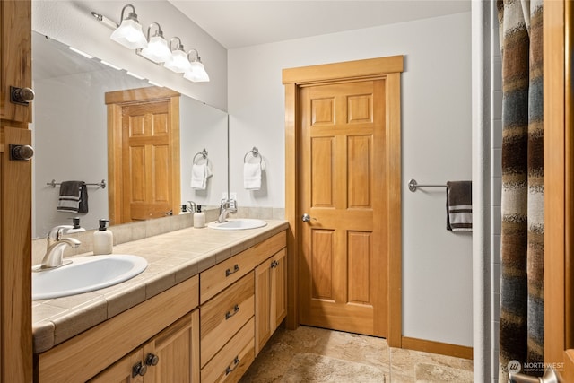 bathroom with double vanity, a sink, and baseboards