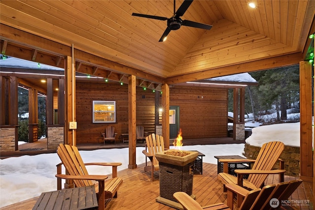 snow covered patio featuring ceiling fan, a fire pit, and a wooden deck