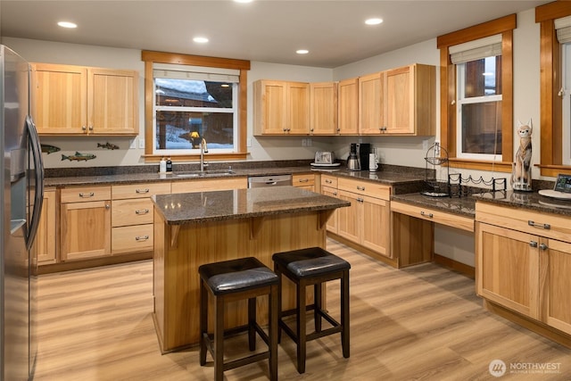 kitchen with a breakfast bar, a sink, a kitchen island, stainless steel fridge with ice dispenser, and dark stone counters