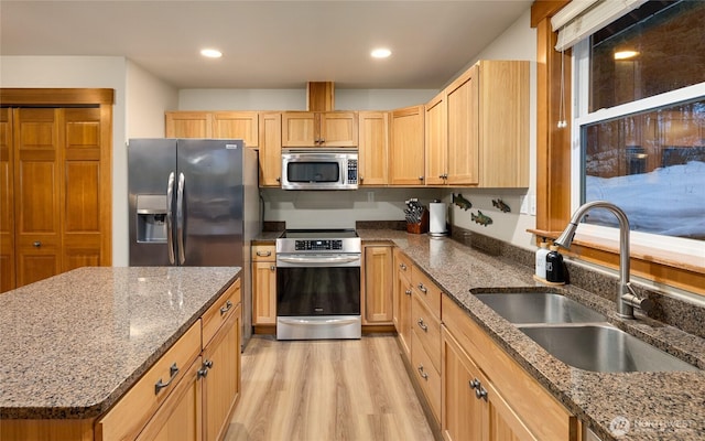 kitchen with stone countertops, recessed lighting, a sink, appliances with stainless steel finishes, and light wood finished floors