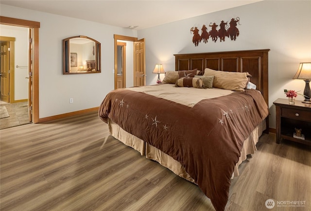 bedroom with ensuite bathroom, baseboards, and wood finished floors