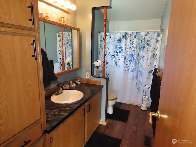 bathroom featuring walk in shower, wood-type flooring, vanity, and toilet