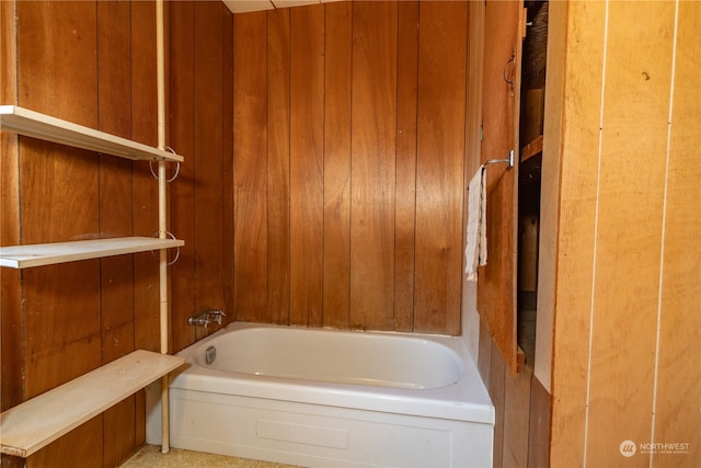 bathroom featuring a tub and wood walls