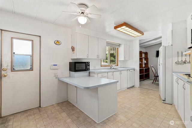 kitchen with white appliances, a peninsula, light countertops, and white cabinets