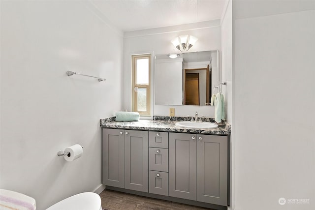 bathroom featuring toilet, wood finished floors, vanity, and baseboards