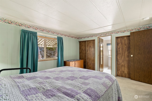 carpeted bedroom with a textured ceiling, ensuite bathroom, and wood walls