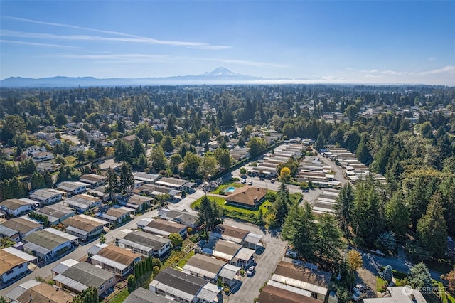 view of property location with a mountain backdrop, nearby suburban area, and a heavily wooded area