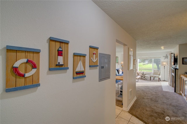 corridor featuring electric panel, light colored carpet, and a textured ceiling