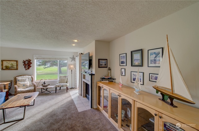 interior space featuring light colored carpet, a tile fireplace, and a textured ceiling