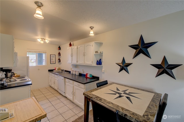 kitchen with light tile patterned flooring, sink, a textured ceiling, white cabinetry, and dishwasher