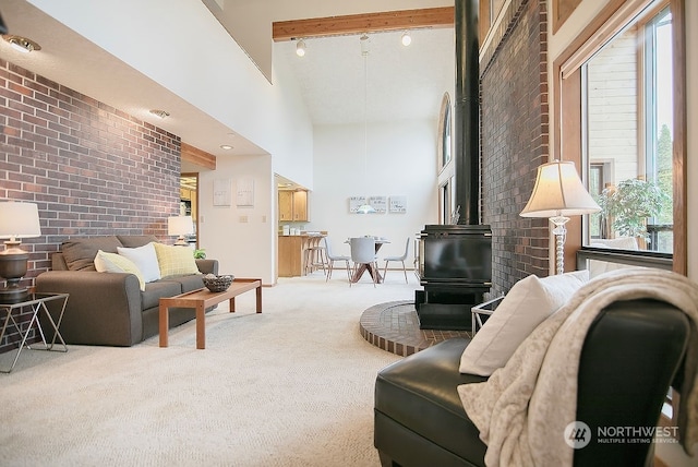 living room with carpet floors, beam ceiling, brick wall, a wood stove, and high vaulted ceiling