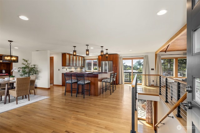 interior space with a notable chandelier, stainless steel refrigerator, light hardwood / wood-style floors, and a breakfast bar area