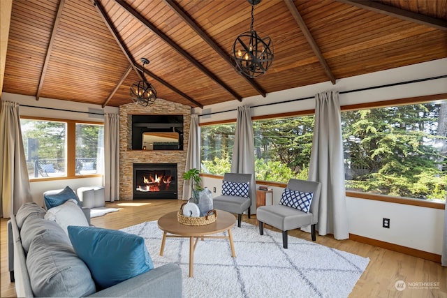 sunroom / solarium featuring a notable chandelier, a healthy amount of sunlight, a stone fireplace, and wooden ceiling