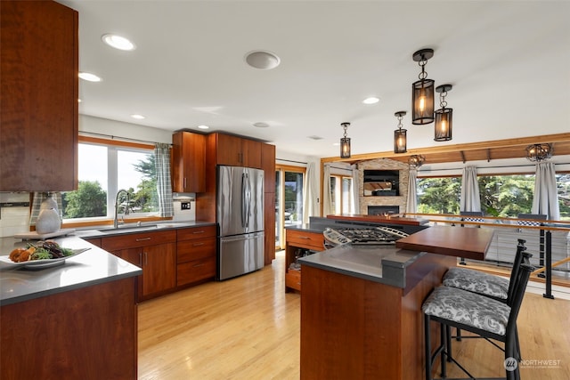 kitchen with light hardwood / wood-style floors, stainless steel appliances, hanging light fixtures, and sink