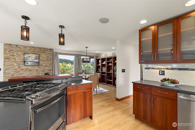 kitchen with pendant lighting, backsplash, appliances with stainless steel finishes, and light wood-type flooring