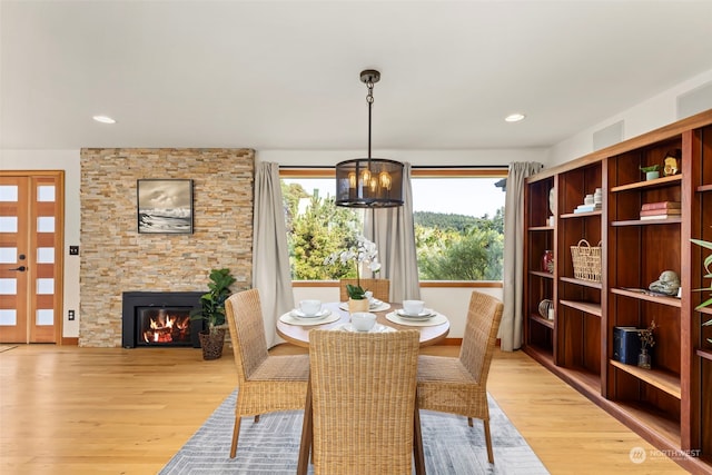 dining area featuring light wood-type flooring, a fireplace, and a chandelier