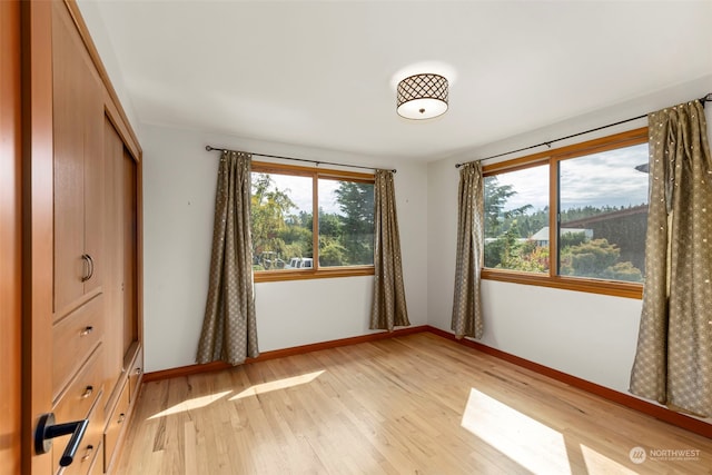 unfurnished bedroom with a closet, light hardwood / wood-style flooring, and multiple windows