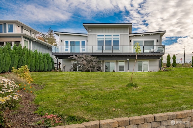 rear view of house featuring a balcony and a lawn