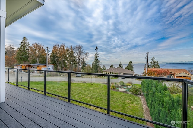 wooden terrace with a water view and a yard