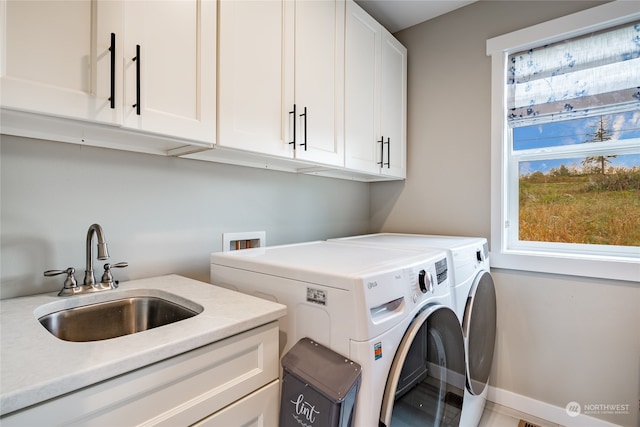 clothes washing area with washing machine and clothes dryer, sink, and cabinets