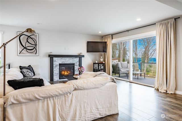 living room with a stone fireplace and dark wood-type flooring