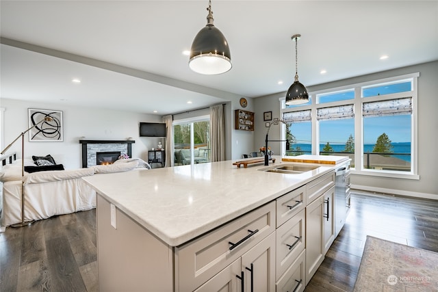 kitchen with pendant lighting, dark hardwood / wood-style flooring, and a center island with sink