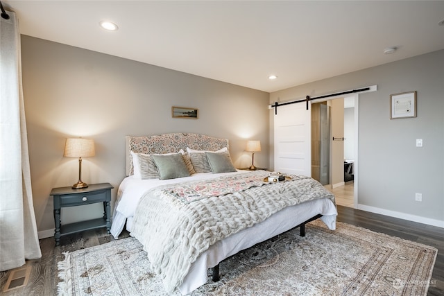 bedroom featuring a barn door and dark wood-type flooring