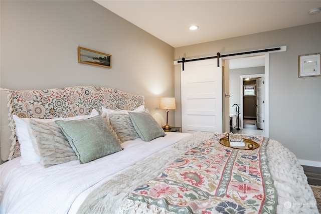 bedroom with a barn door and hardwood / wood-style flooring