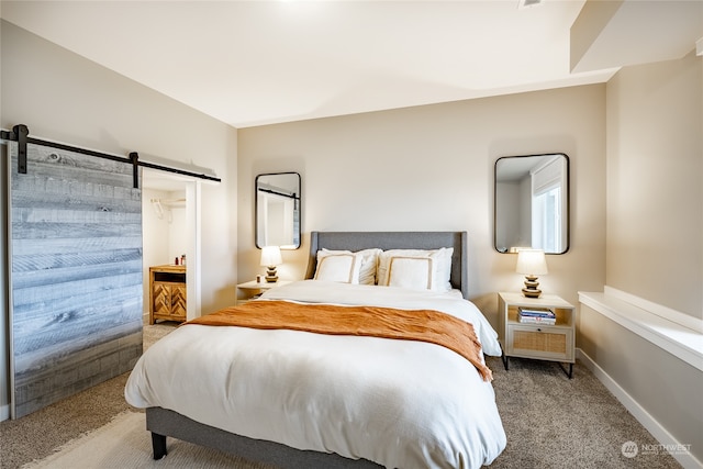 carpeted bedroom featuring a barn door and ensuite bath