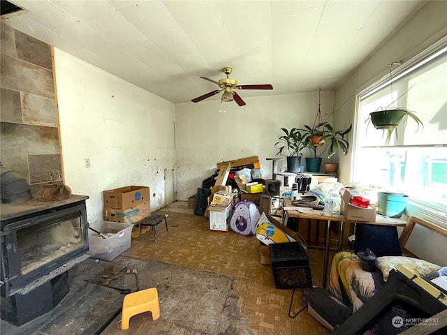 miscellaneous room featuring ceiling fan, plenty of natural light, and a wood stove