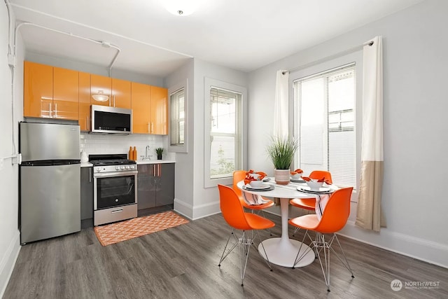 kitchen featuring dark hardwood / wood-style floors, light brown cabinets, stainless steel appliances, and tasteful backsplash