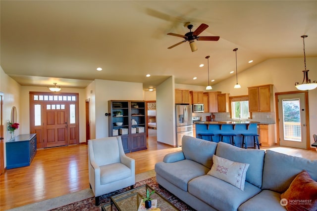 living room featuring light hardwood / wood-style floors, vaulted ceiling, and ceiling fan