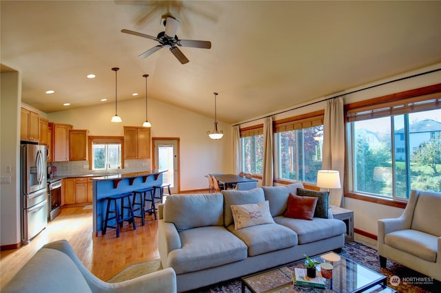 living room with light hardwood / wood-style flooring, ceiling fan, vaulted ceiling, and sink