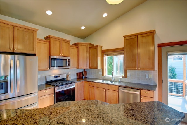 kitchen with sink, stainless steel appliances, backsplash, and dark stone countertops