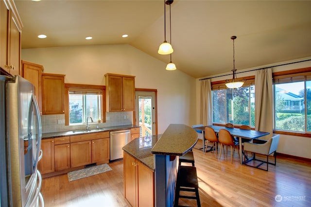 kitchen featuring lofted ceiling, a kitchen island, light hardwood / wood-style flooring, stainless steel appliances, and decorative light fixtures