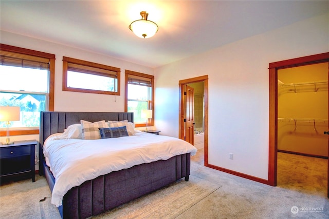 bedroom with connected bathroom, light carpet, multiple windows, and a closet