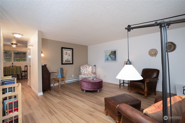 sitting room with a baseboard heating unit, light hardwood / wood-style floors, and a textured ceiling