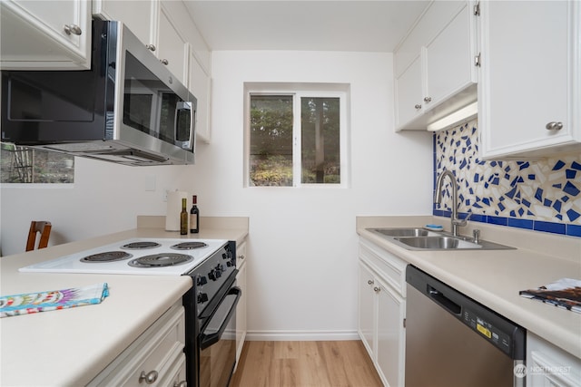 kitchen featuring white cabinets, sink, light hardwood / wood-style flooring, backsplash, and appliances with stainless steel finishes