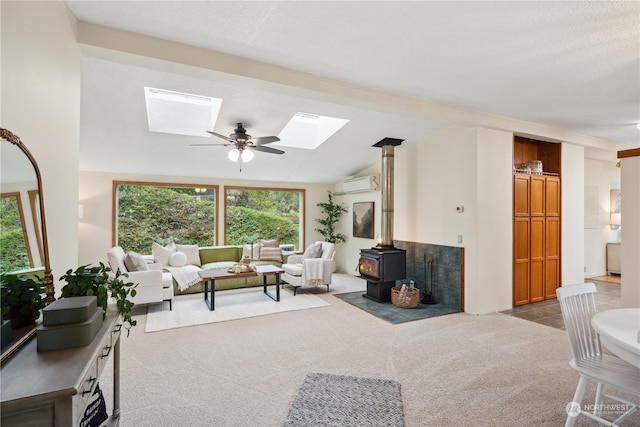 living room featuring a wall mounted air conditioner, a wood stove, light carpet, ceiling fan, and vaulted ceiling with skylight