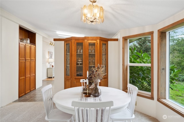 dining space with a textured ceiling, an inviting chandelier, and light colored carpet