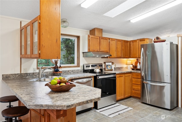 kitchen featuring sink, appliances with stainless steel finishes, kitchen peninsula, and a textured ceiling