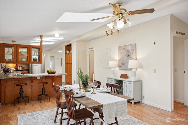 dining space featuring light hardwood / wood-style flooring, ceiling fan, and a skylight